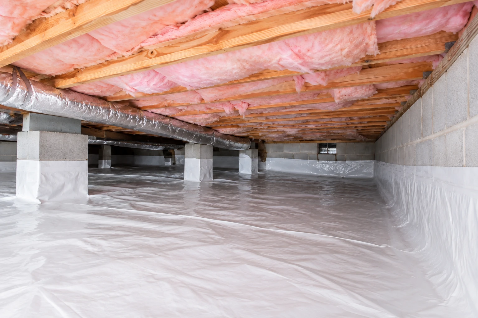Crawl space with pink insulation between ceiling joists, a silver duct, and white vapor barrier covering the floor and lower walls.